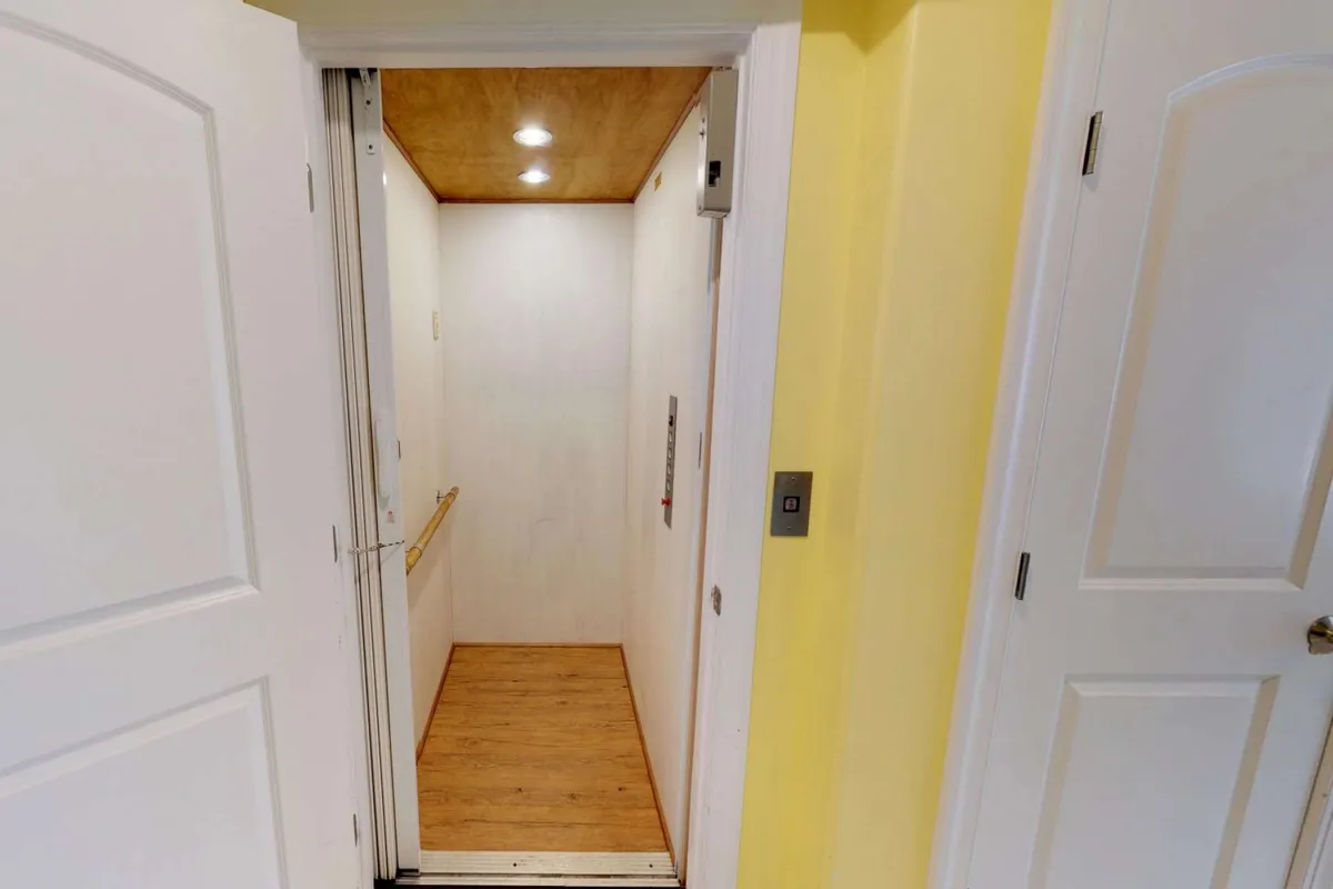 The interior view of an elevator with its door open, warmly lit and accentuated by clean wooden flooring. The scene is accessible and inviting, suggesting ease of movement and welcoming access for all guests.