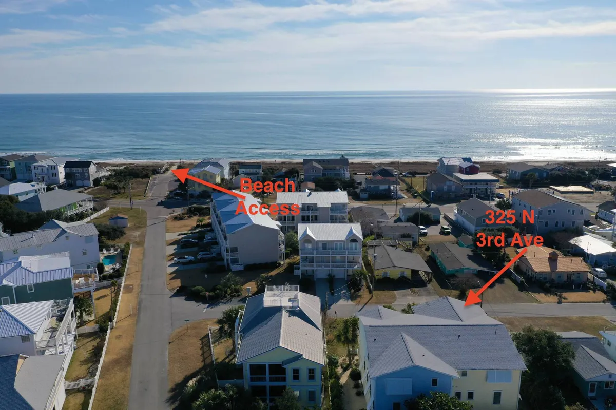 An exterior perspective highlighting easy beach access, with a clear view of the ocean, residential architecture, and families engaging in beach activities like sandcastle building and outdoor relaxation. The mood is bright and welcoming, reflecting a seamless connection from home to sand.